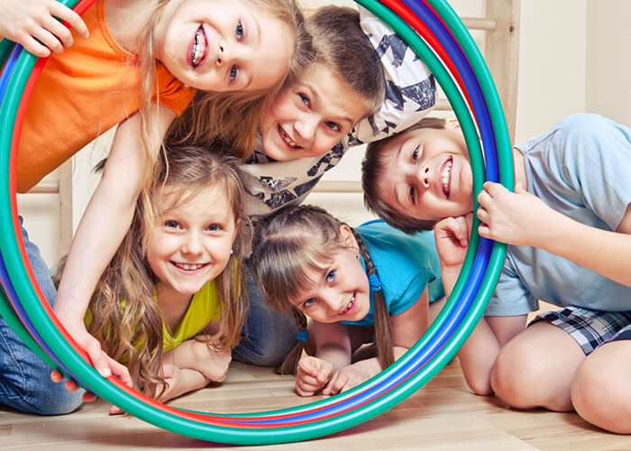  5 kids holding a their hula hoop together while smiling  Img title: kids in the hula hoop